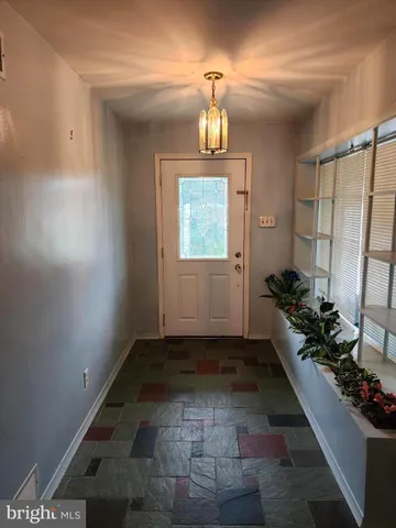 an empty room with a chandelier fan and windows