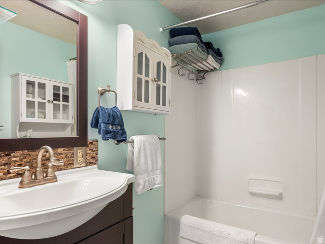 371 Lewis Loop, Unit 29 Fish Haven, ID 83287 - Photo 29 of 40 Bathroom featuring a white drop-in sink, a two-handle brushed nickel faucet, and a stone-look tile backsplash