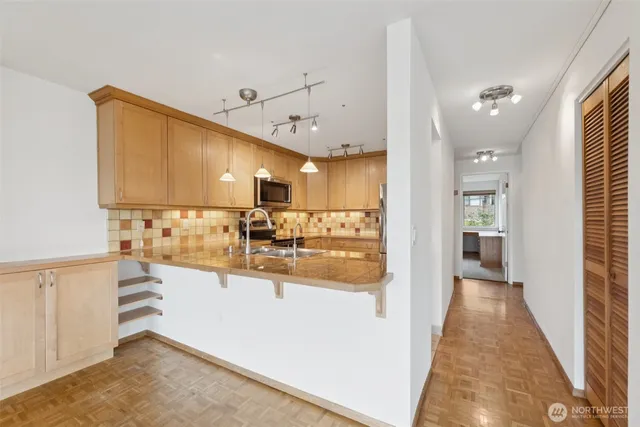 a view of a kitchen with kitchen island a sink wooden floor and counter top space