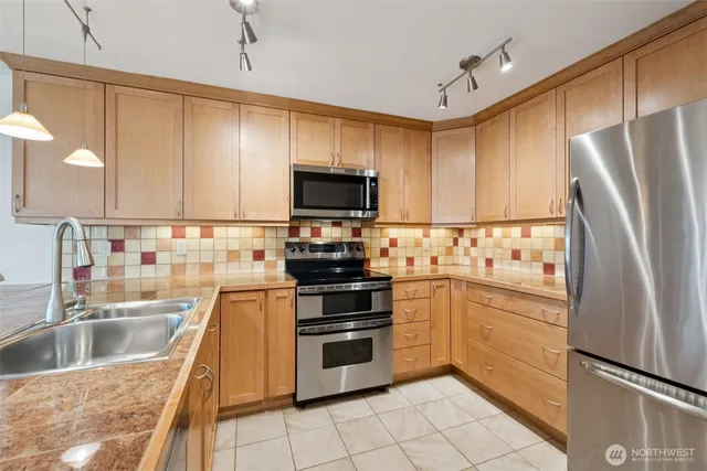 a kitchen with granite countertop a refrigerator a sink and white cabinets