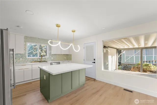 a kitchen with a stove a refrigerator a sink and dishwasher with wooden floor