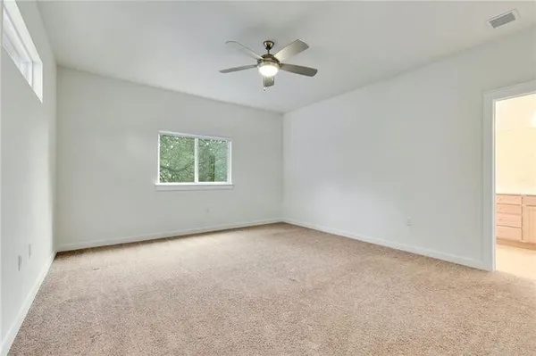 a view of an empty room and kitchen with wooden floor