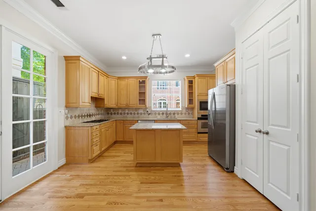 a kitchen with stainless steel appliances granite countertop a refrigerator a sink dishwasher a stove with white cabinets and wooden floor