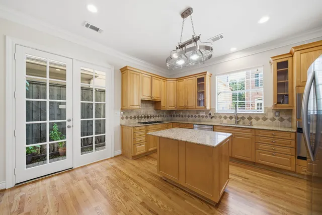 a large kitchen with kitchen island granite countertop a large window and stainless steel appliances
