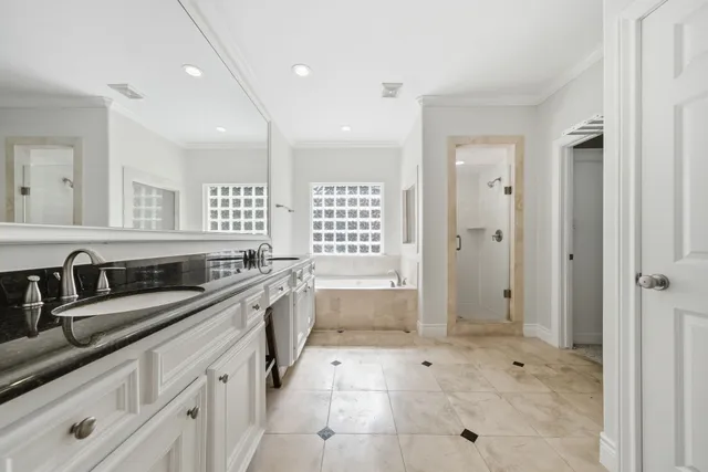 a large white bathroom with a granite countertop sink a toilet a mirror and shower
