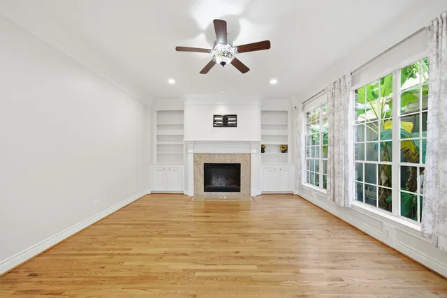a view of a livingroom with a fireplace a ceiling fan and windows