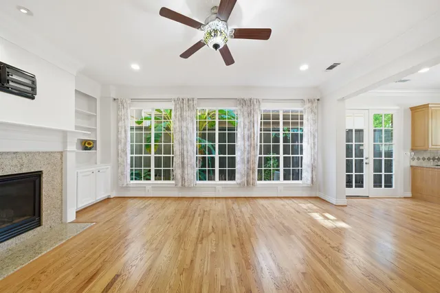 a view of an empty room with wooden floor and a fireplace