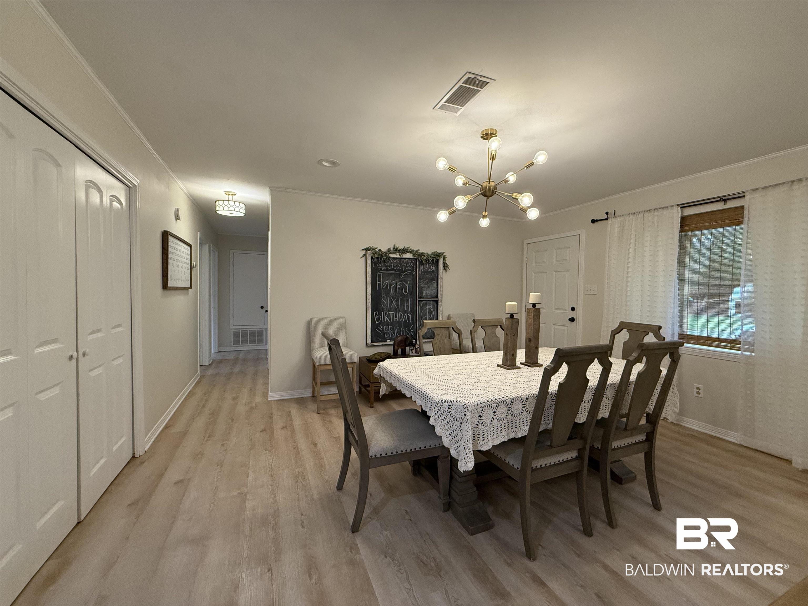 90 Florida Street Monroeville, AL 36460 - Photo 22 of 31 Dining room featuring ornamental molding, a notable chandelier, and light wood-type flooring