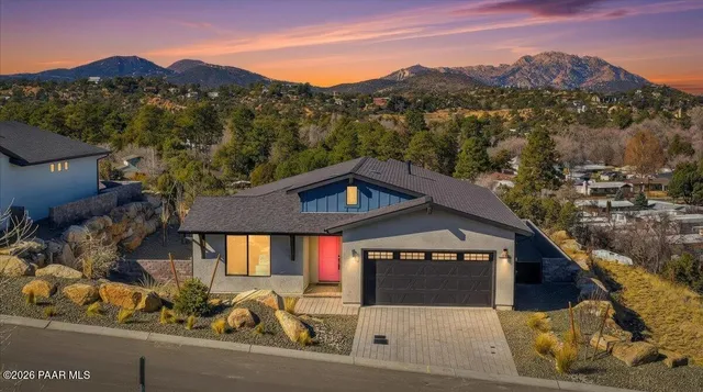 a front view of a house with a yard and mountain view in back