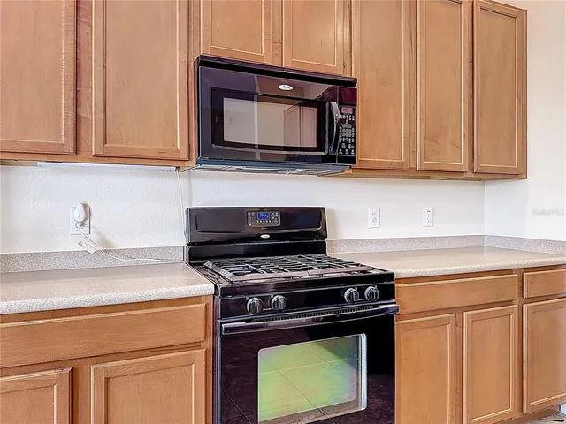 a kitchen with granite countertop a refrigerator stove and microwave
