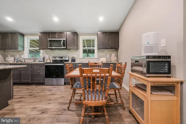 a kitchen with stainless steel appliances granite countertop a stove top oven a sink a dining table and chairs