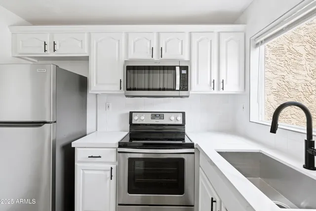 a kitchen with granite countertop white cabinets and stainless steel appliances