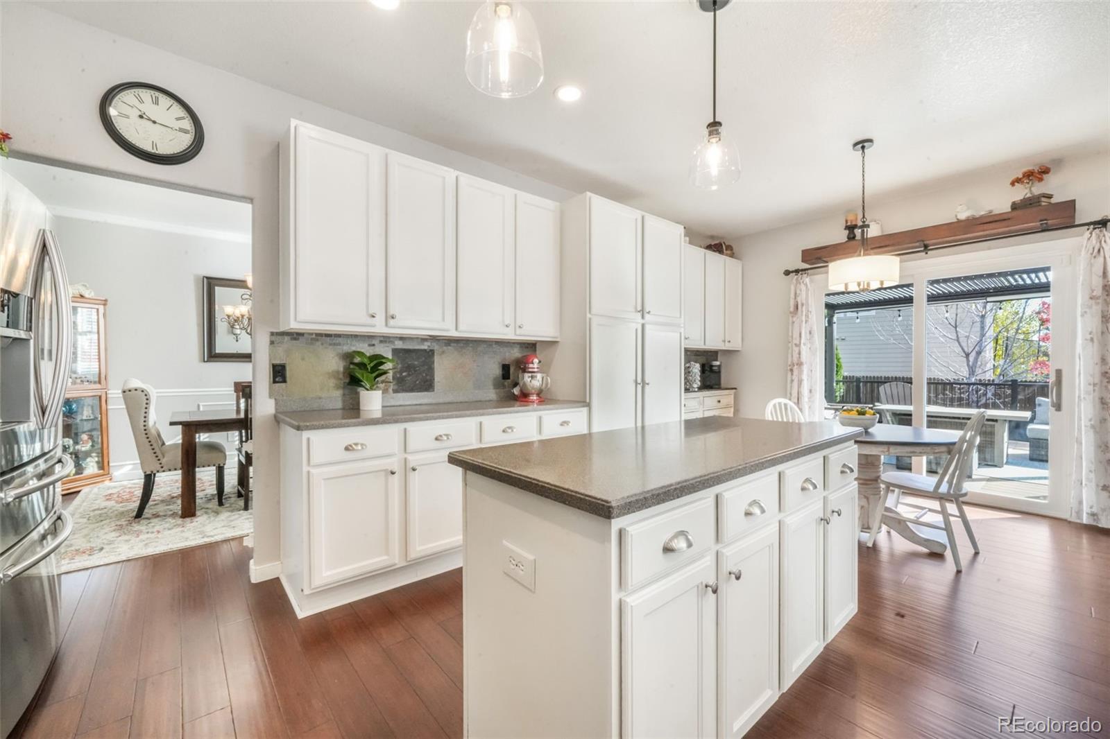4457 Centerville Drive Colorado Springs, CO 80922 - Photo 11 of 50 a kitchen with stainless steel appliances granite countertop a stove a sink a dining table and chairs with wooden floor