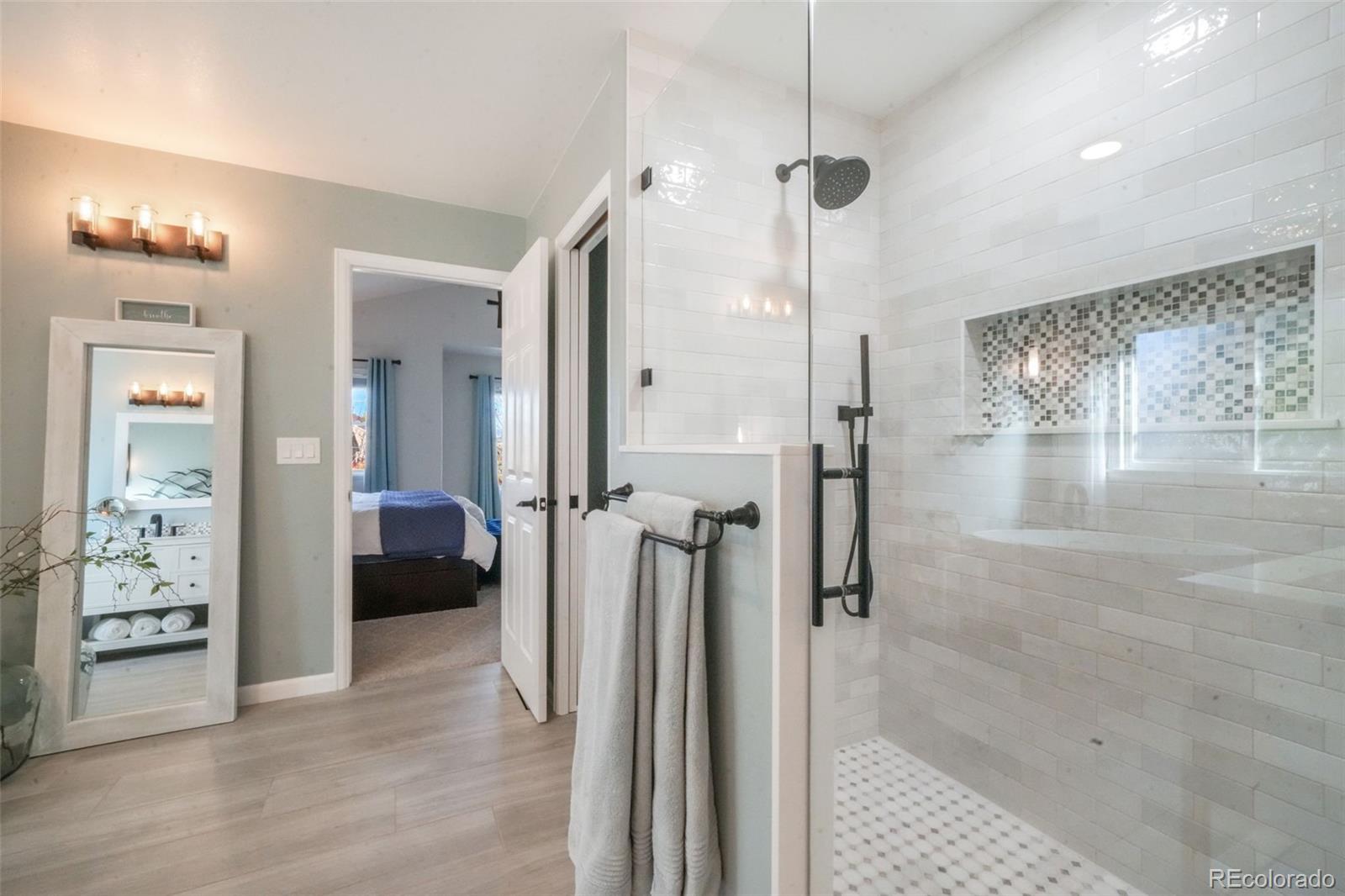 4457 Centerville Drive Colorado Springs, CO 80922 - Photo 31 of 50 a spacious bathroom with a glass shower door a sink and a mirror