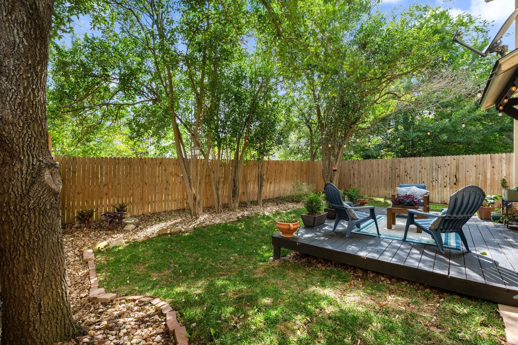 6708 Menchaca Road, Unit 2 Austin, TX 78745 - Photo 26 of 30 Private backyard featuring a dark composite deck, manicured lawn, and mature trees