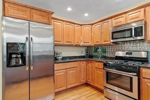 a kitchen with stainless steel appliances granite countertop a stove microwave and refrigerator