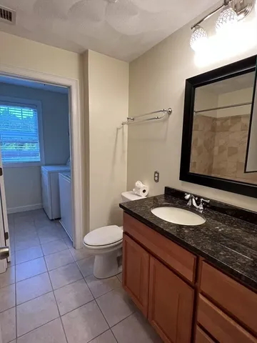 a bathroom with a granite countertop sink a toilet and a mirror