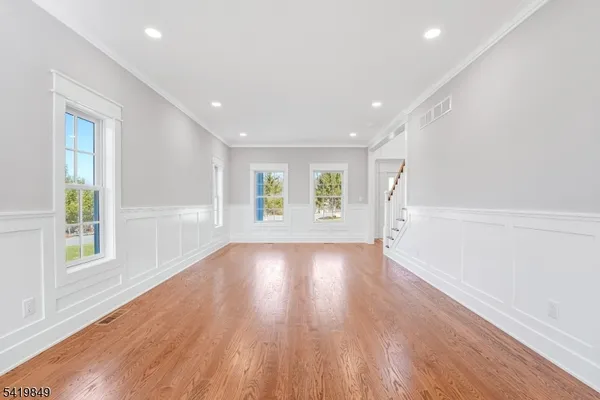 a view of an empty room with wooden floor and windows