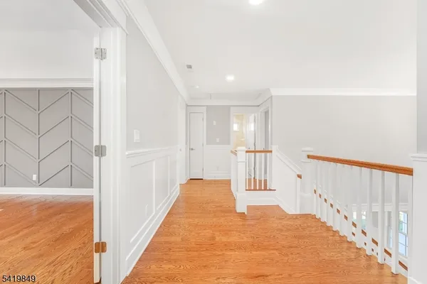 a view of a hallway with wooden floor and staircase