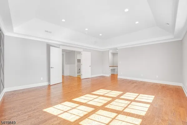 a view of an empty room with wooden floor and closet