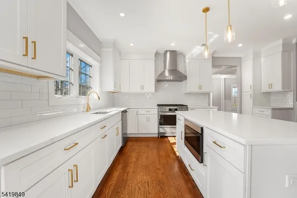 a large kitchen with stainless steel appliances lots of white cabinets and a chandelier