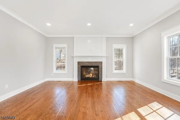 an empty room with wooden floor fireplace and windows