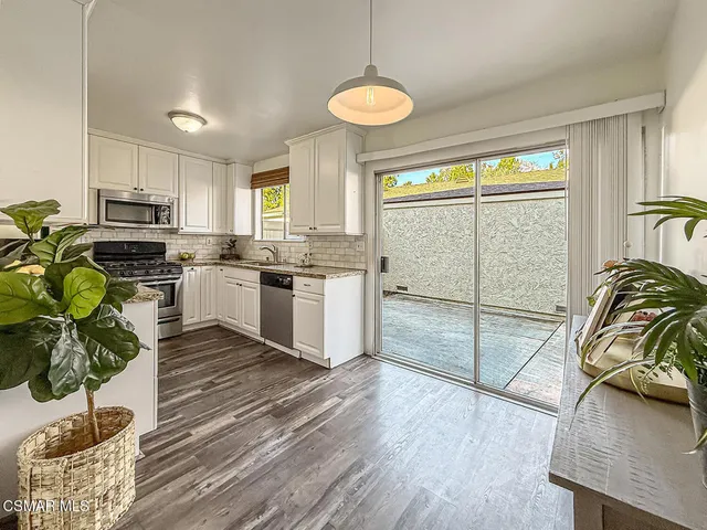 a kitchen with stainless steel appliances granite countertop a stove a sink a refrigerator cabinets and wooden floor