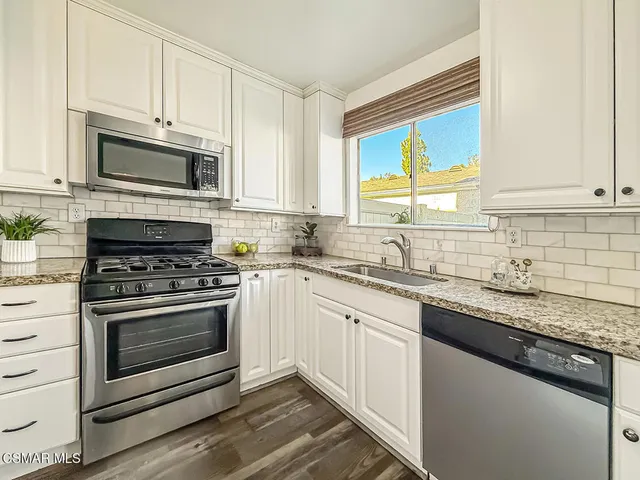 a kitchen with cabinets stainless steel appliances a sink and a window