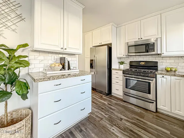 a kitchen with granite countertop white cabinets and stainless steel appliances