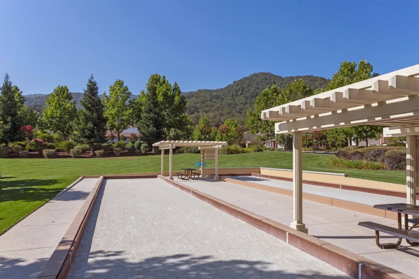 7217 Pitlochry Drive Gilroy, CA 95020 - Photo 55 of 66 a wooden bench sitting in a park with plants and large trees