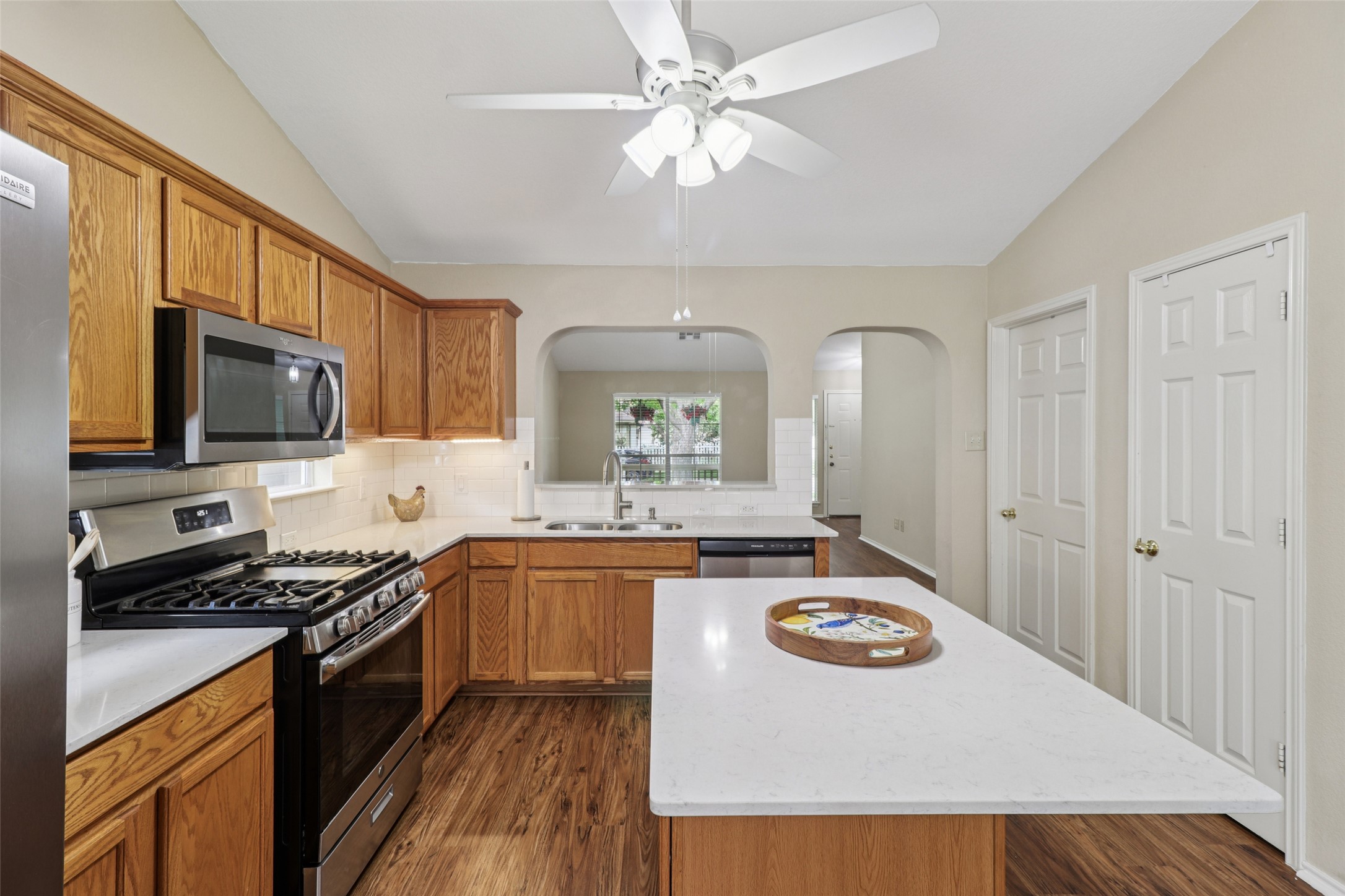 700 Scheel Road Kyle, TX 78640 - Photo 16 of 39 The kitchen features wood cabinetry, stainless steel appliances, and white countertops, complemented by wood flooring and a ceiling fan