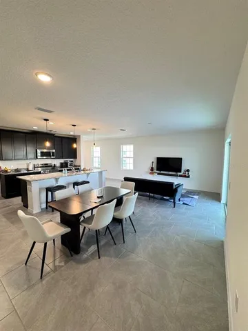 a living room with furniture a table and kitchen view