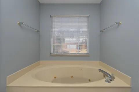 a spacious bathroom with a tub sink and mirror