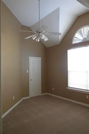 en empty room with windows and chandelier fan