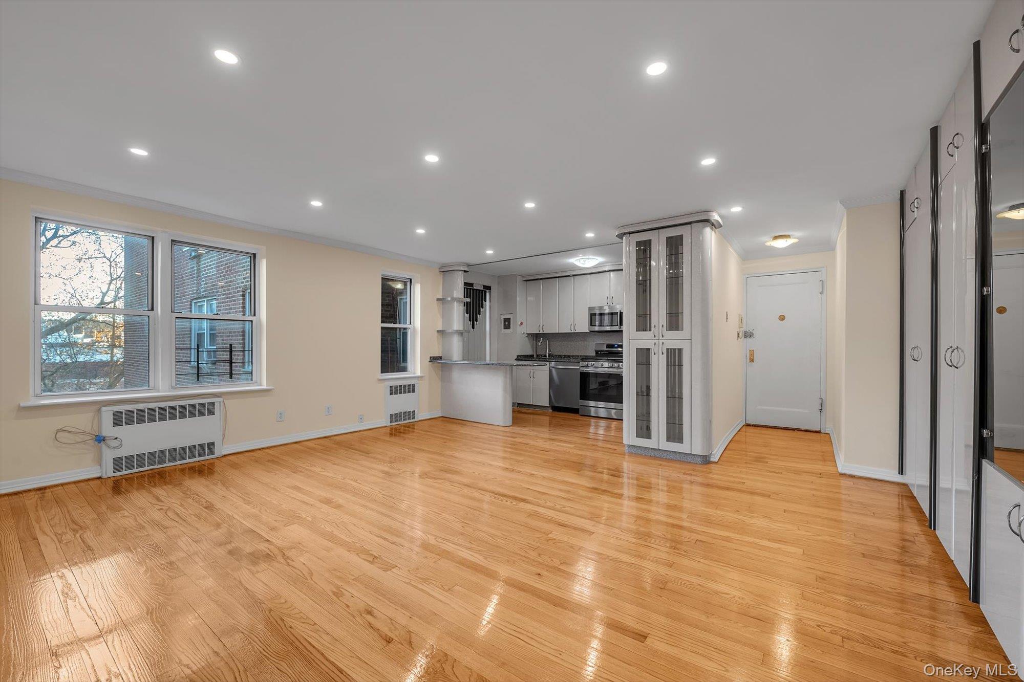 65-35 Yellowstone Boulevard, Unit 4G Queens, NY 11375 - Photo 3 of 10 Unfurnished living room with radiator, light wood-type flooring, recessed lighting, and crown molding