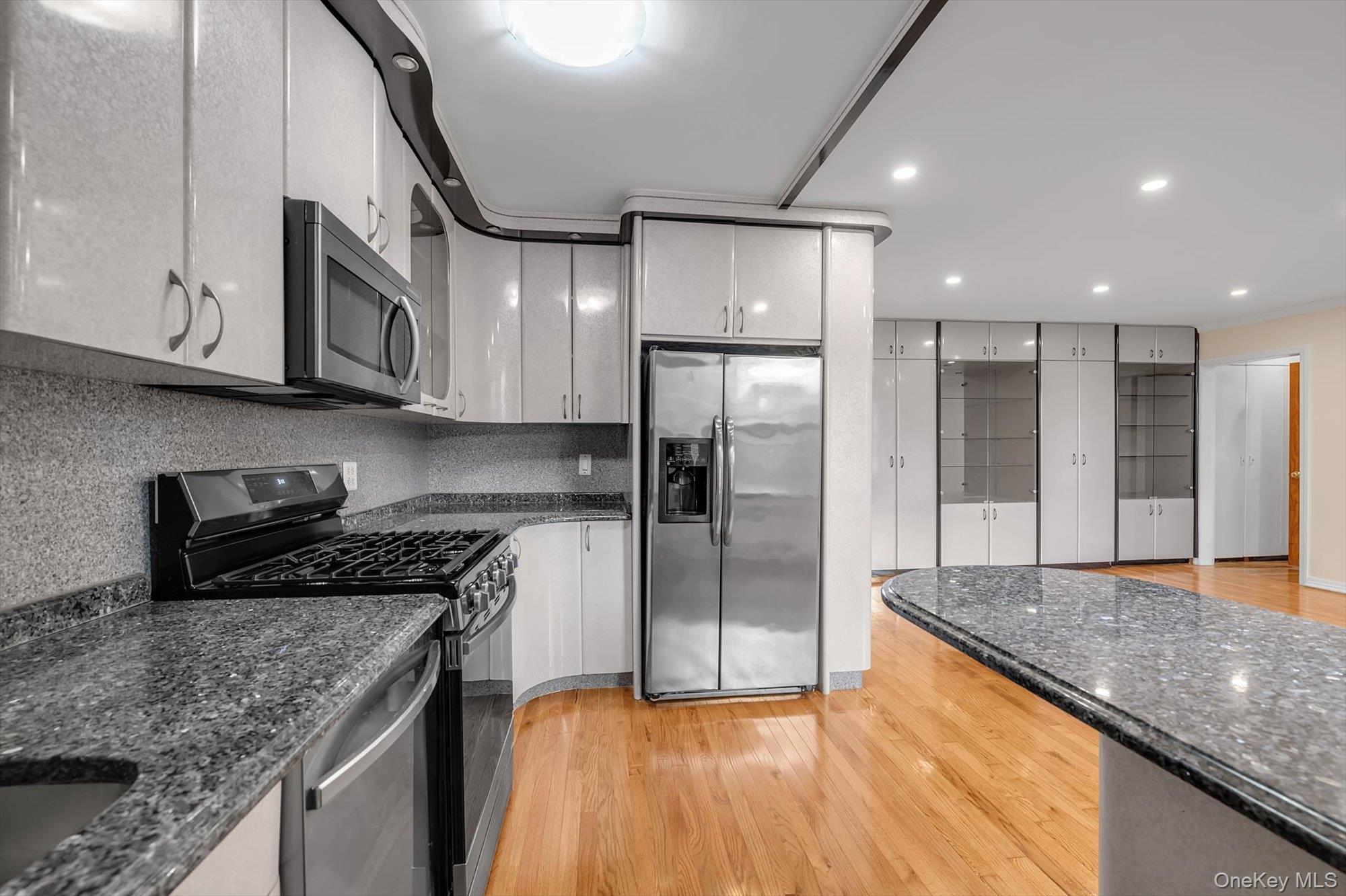 65-35 Yellowstone Boulevard, Unit 4G Queens, NY 11375 - Photo 6 of 10 Kitchen featuring light wood-type flooring, stainless steel appliances, dark stone counters, and recessed lighting