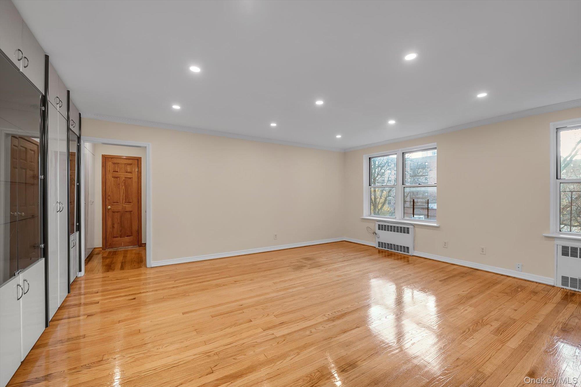 65-35 Yellowstone Boulevard, Unit 4G Queens, NY 11375 - Photo 7 of 10 Unfurnished living room with light wood finished floors, recessed lighting, crown molding, and radiator heating unit