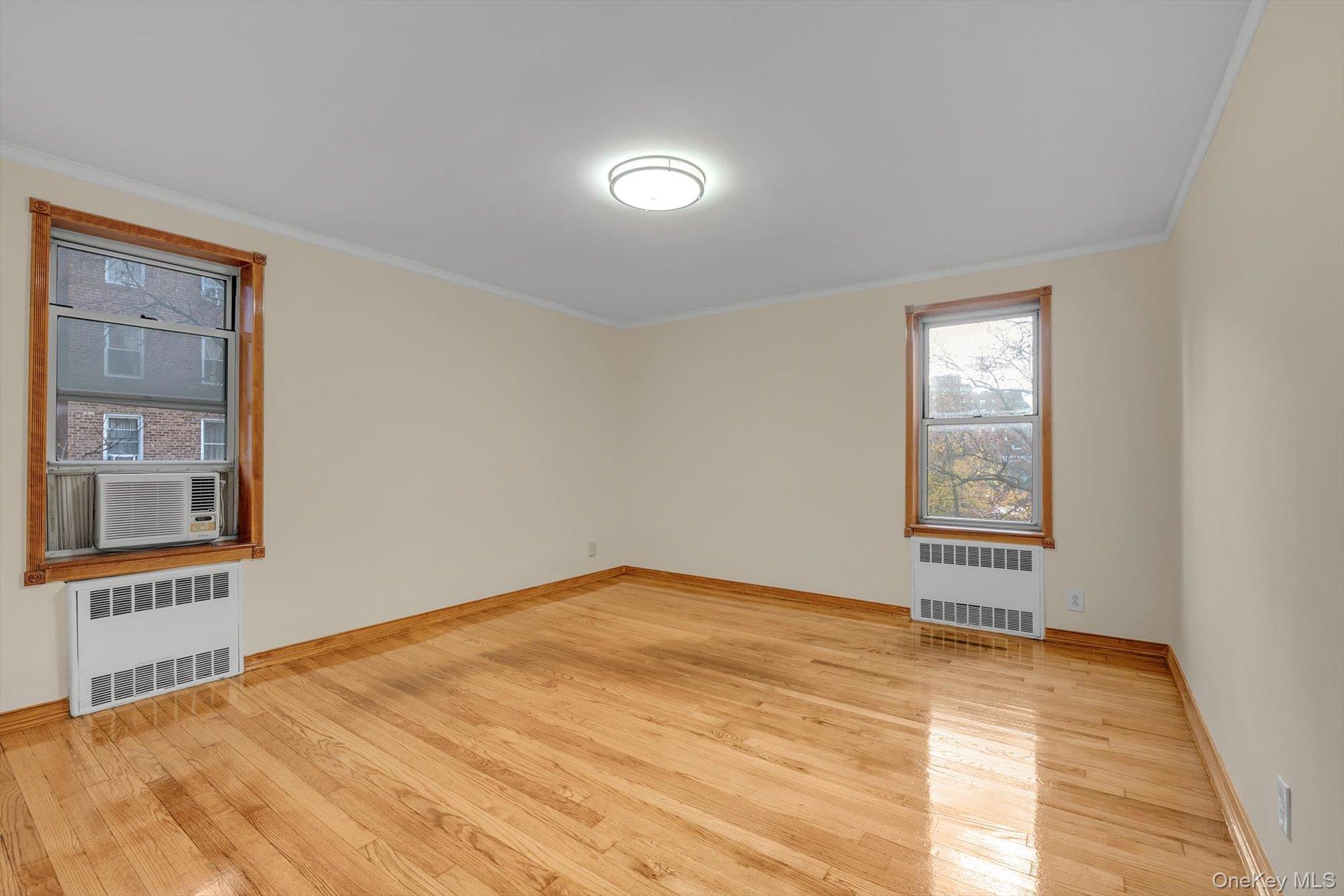 65-35 Yellowstone Boulevard, Unit 4G Queens, NY 11375 - Photo 8 of 10 Spare room featuring radiator, light wood-style floors, and crown molding