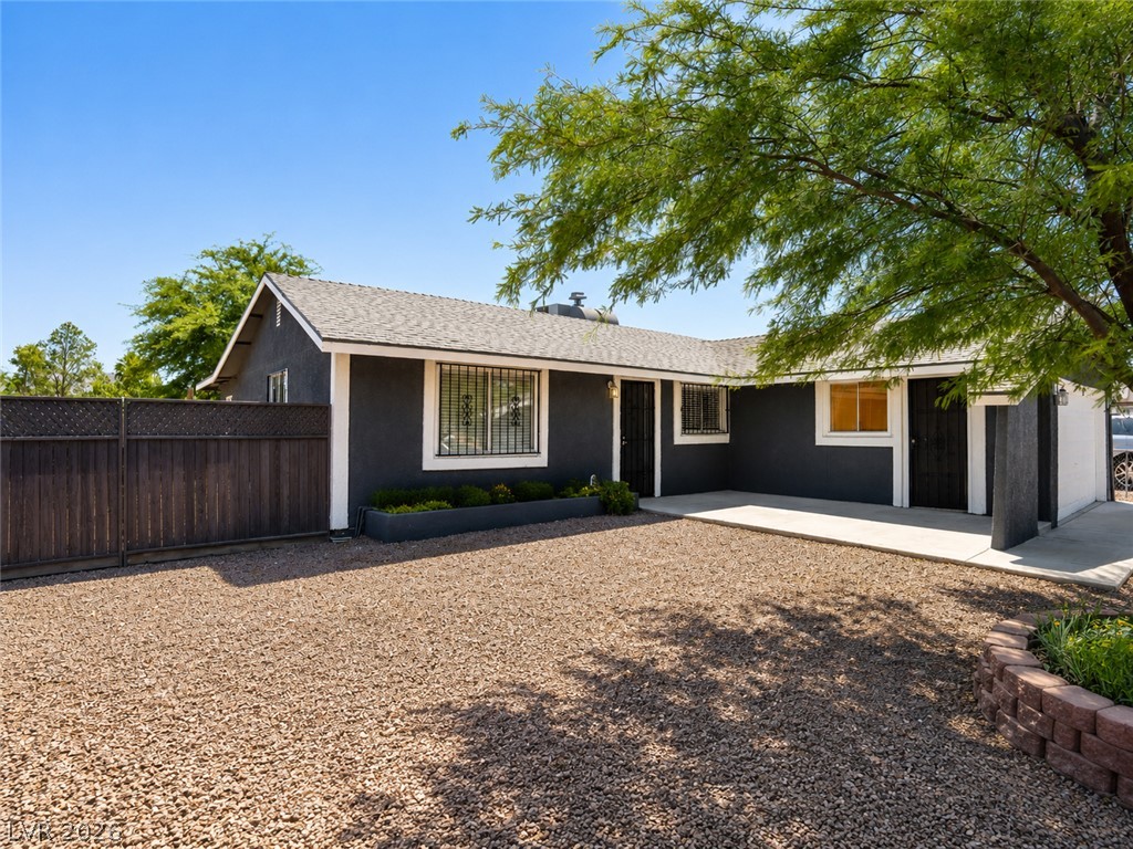 2870 South Sandhill Road Las Vegas, NV 89121 - Photo 2 of 64 A well-maintained facade features secure windows, a wooden fence, and a gravel driveway.