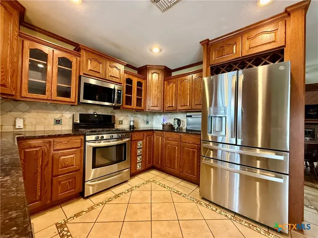 a kitchen with stainless steel appliances granite countertop a refrigerator stove and sink