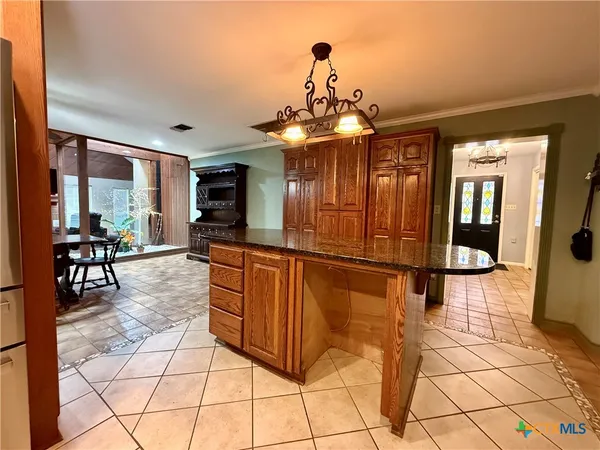 a dining hall with granite countertop a refrigerator and cabinets