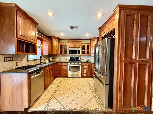 a kitchen with stainless steel appliances granite countertop a refrigerator and a stove top oven