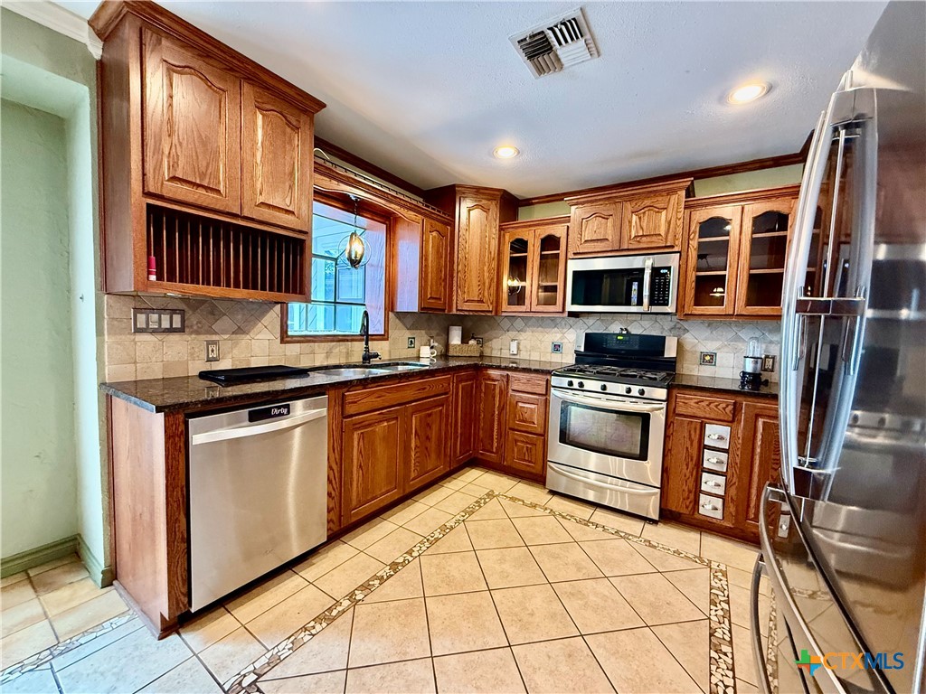 20 Hambleton Road Victoria, TX 77905 - Photo 10 of 42 a kitchen with stainless steel appliances granite countertop a stove top oven a sink dishwasher a dining table and chairs with wooden floor