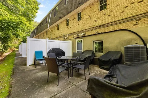 a patio with table and chairs and potted plants