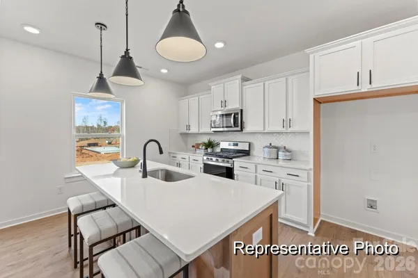 a kitchen with stainless steel appliances granite countertop a sink a stove a refrigerator cabinets and chairs