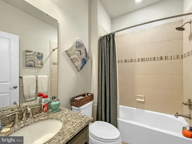 a bathroom with a granite countertop sink mirror vanity and toilet