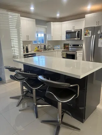 a kitchen with stainless steel appliances a table chairs microwave and refrigerator