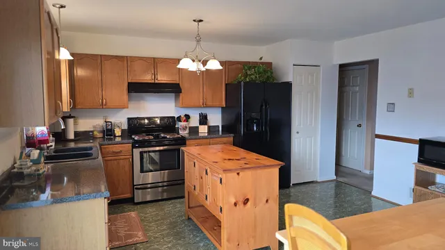 a kitchen with stainless steel appliances kitchen island granite countertop a refrigerator a stove top oven a sink and dishwasher