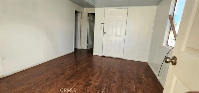 a view of a hallway with wooden floor and a bathroom