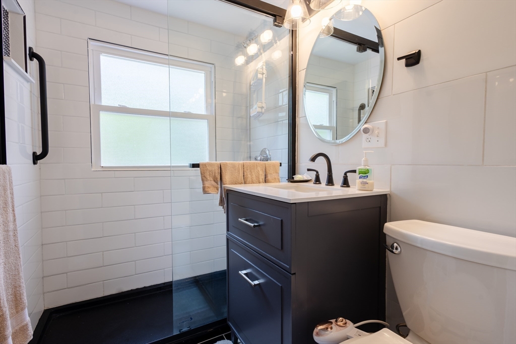 30 Leighton Road Boston, MA 02136 - Photo 23 of 38 a bathroom with a sink a mirror a toilet and a window